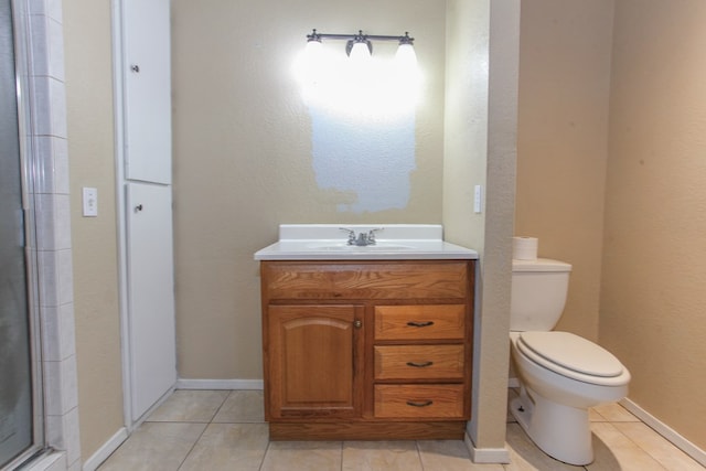 bathroom featuring tile patterned flooring, vanity, toilet, and a shower with shower door