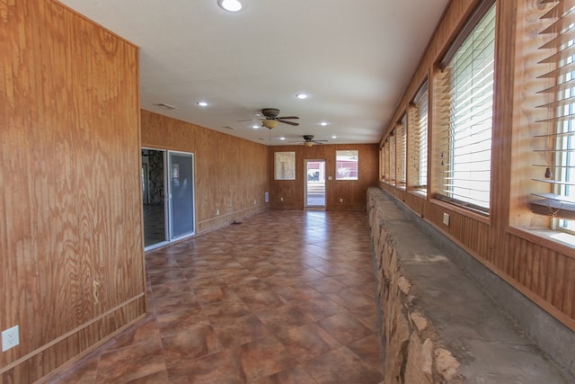 interior space with wood walls, plenty of natural light, and ceiling fan