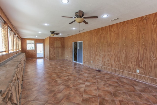 unfurnished living room featuring wood walls and ceiling fan