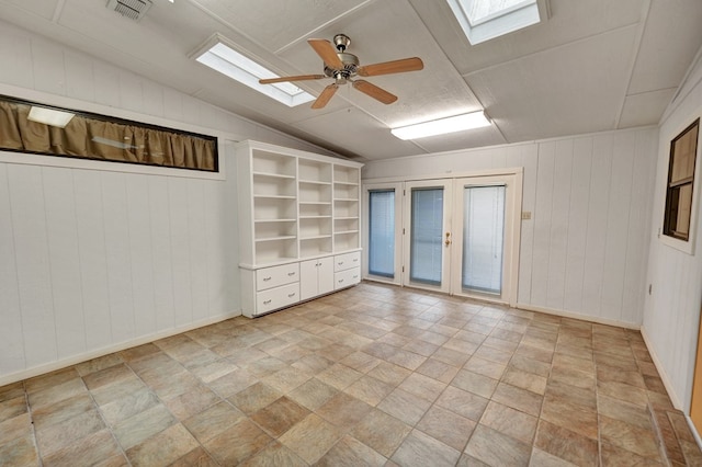 spare room with vaulted ceiling with skylight, ceiling fan, and french doors