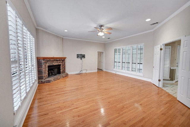 unfurnished living room featuring crown molding, a brick fireplace, ceiling fan, and light hardwood / wood-style flooring