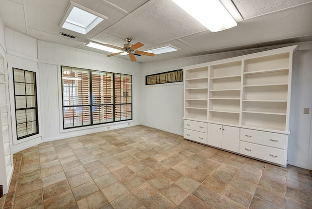 interior space featuring ceiling fan and wooden walls