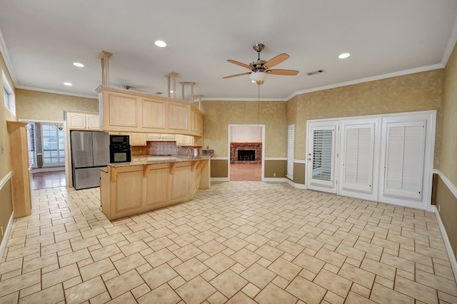 kitchen featuring black appliances, ornamental molding, ceiling fan, kitchen peninsula, and light brown cabinets