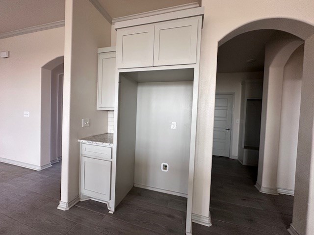 3210 Fordham Ave, Big Spring, TX 79720 - kitchen featuring white cabinets, ornamental molding, dark wood-type flooring, and light stone counters