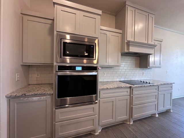 3210 Fordham Ave, Big Spring, TX 79720 - kitchen featuring stainless steel appliances, ornamental molding, dark wood-type flooring, tasteful backsplash, and light stone counters