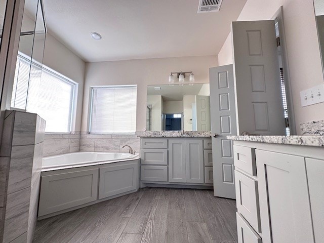 3210 Fordham Ave, Big Spring, TX 79720 - full bathroom with vanity, a garden tub, and wood finished floors