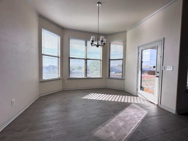 3210 Fordham Ave, Big Spring, TX 79720 - unfurnished dining area featuring crown molding, dark wood-style floors, and a chandelier