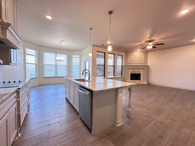3210 Fordham Ave, Big Spring, TX 79720 - kitchen with stainless steel dishwasher, ceiling fan, dark wood finished floors, a fireplace, and an island with sink