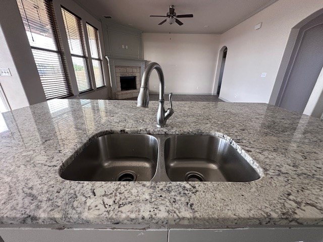 3210 Fordham Ave, Big Spring, TX 79720 - kitchen view of light stone countertops, ceiling fan, a fireplace, and arched walkways