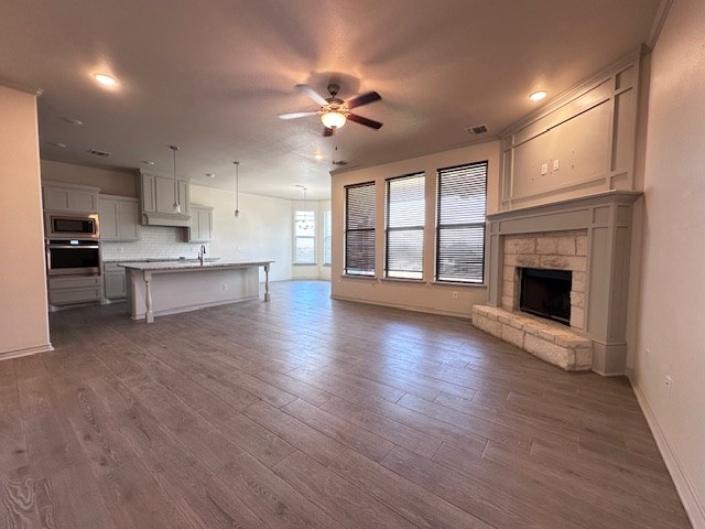 3210 Fordham Ave, Big Spring, TX 79720 - unfurnished living room with ceiling fan, dark wood-style floors, a fireplace, and recessed lighting