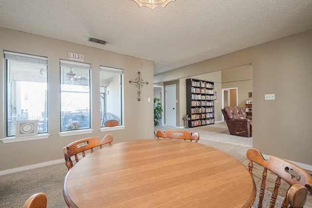 dining area with baseboards, a textured ceiling, visible vents, and carpet flooring