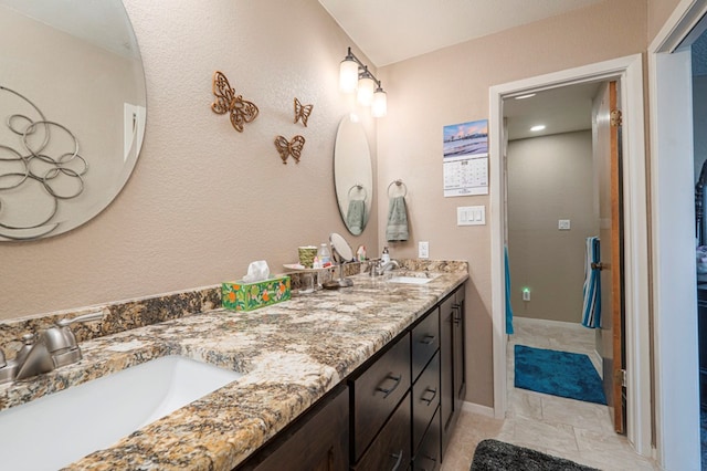 bathroom with double vanity, a sink, and baseboards