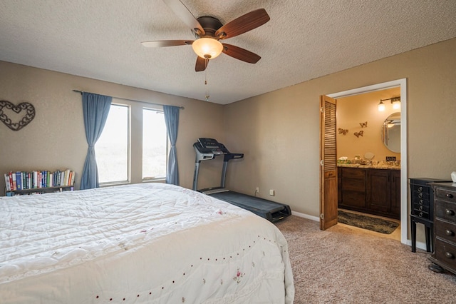 bedroom with a textured ceiling, ensuite bathroom, light carpet, a ceiling fan, and baseboards