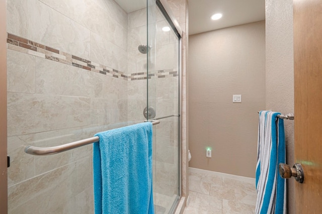full bath featuring toilet, a stall shower, and baseboards
