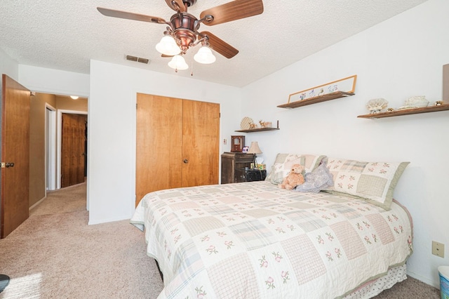 bedroom with a closet, visible vents, a ceiling fan, light carpet, and a textured ceiling