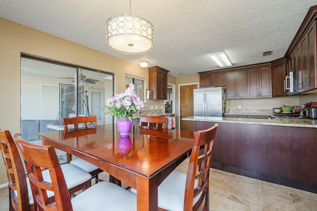 dining space with ceiling fan, visible vents, and a textured ceiling