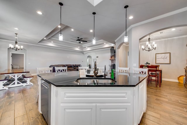 kitchen featuring crown molding, light wood-style floors, arched walkways, white cabinets, and a sink