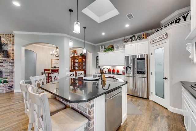 kitchen with visible vents, a sink, a kitchen breakfast bar, dark countertops, and stainless steel appliances