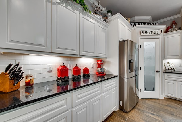 kitchen with wood finished floors, white cabinets, stainless steel fridge with ice dispenser, and ornamental molding