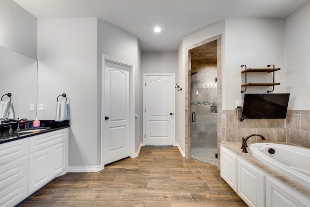 full bath with a garden tub, wood finished floors, a shower stall, baseboards, and vanity