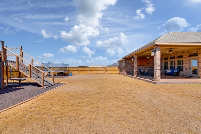 view of yard with a fenced backyard, ceiling fan, a patio, and a trampoline