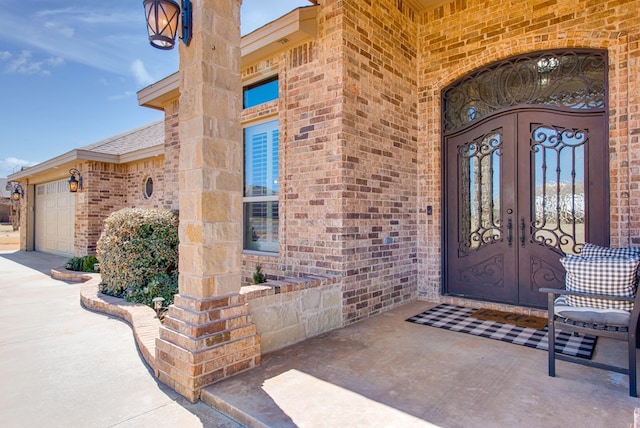 entrance to property featuring brick siding, french doors, and a garage