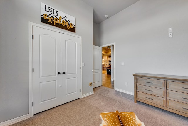 bedroom with baseboards, light carpet, and a closet