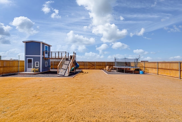 view of jungle gym with a trampoline, a fenced backyard, a lawn, and an outdoor structure