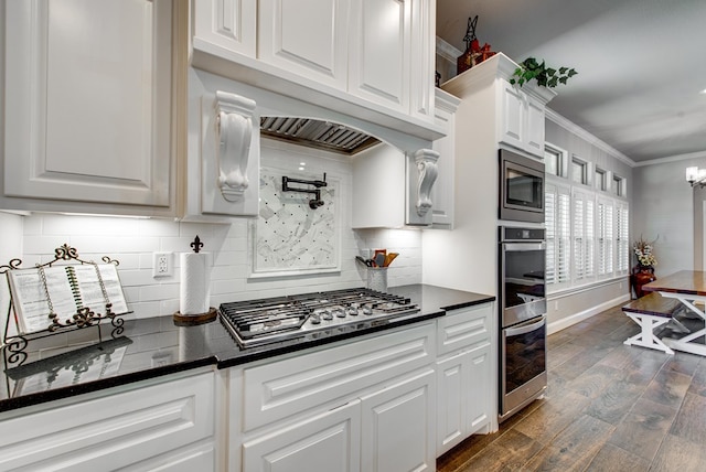 kitchen featuring dark wood-style floors, ornamental molding, white cabinets, appliances with stainless steel finishes, and dark countertops