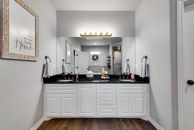 full bathroom featuring wood finished floors, tiled shower, double vanity, and a sink