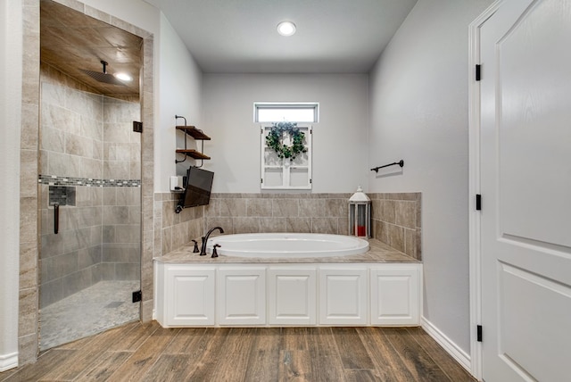 bathroom with a garden tub, wood finished floors, and a stall shower