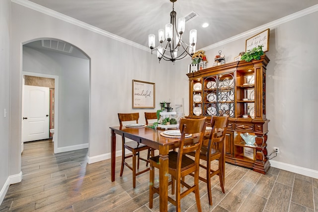 dining space featuring arched walkways, ornamental molding, baseboards, and wood finished floors