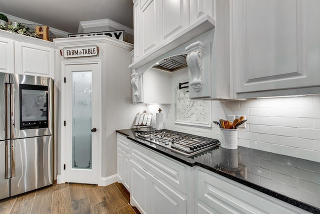 kitchen with dark wood finished floors, decorative backsplash, appliances with stainless steel finishes, white cabinetry, and crown molding