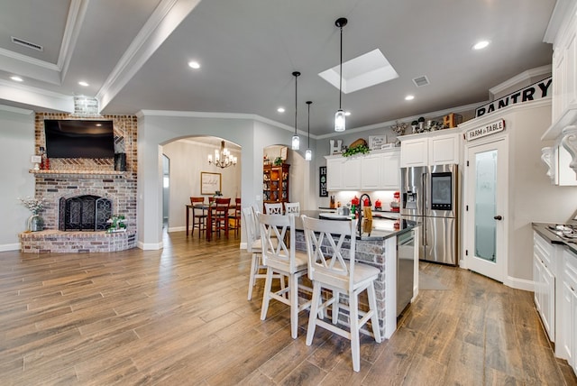 kitchen with visible vents, dark countertops, open floor plan, arched walkways, and appliances with stainless steel finishes