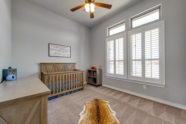 carpeted bedroom with a nursery area, baseboards, and ceiling fan