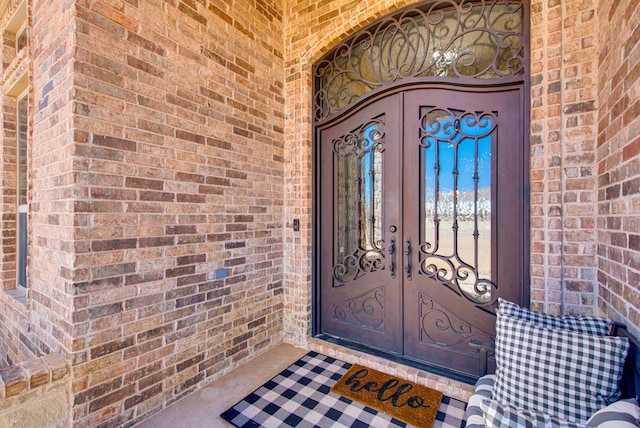 property entrance featuring french doors and brick siding