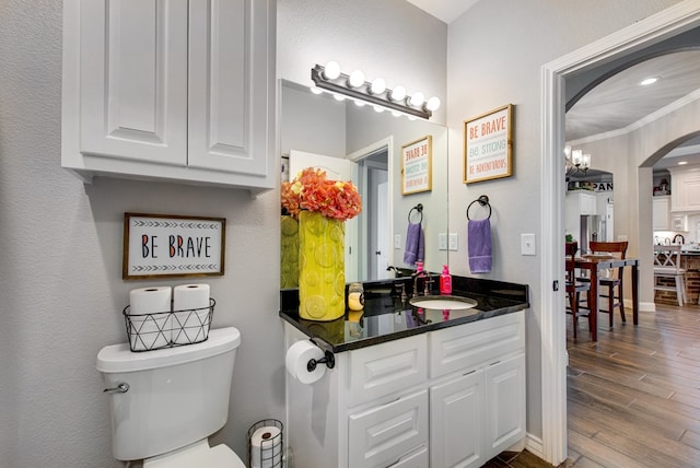 bathroom with toilet, wood finished floors, crown molding, baseboards, and vanity