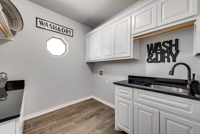 laundry room with baseboards, wood finish floors, washer hookup, cabinet space, and a sink