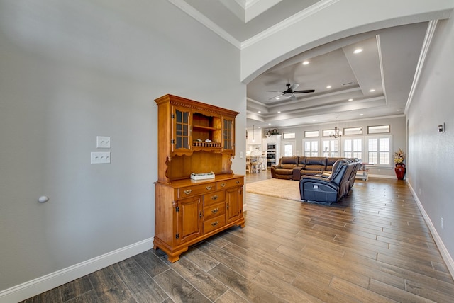 living room with arched walkways, ornamental molding, a raised ceiling, and dark wood-style flooring