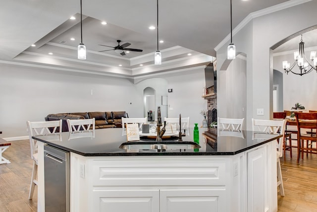 kitchen featuring ornamental molding, a sink, arched walkways, white cabinets, and light wood finished floors