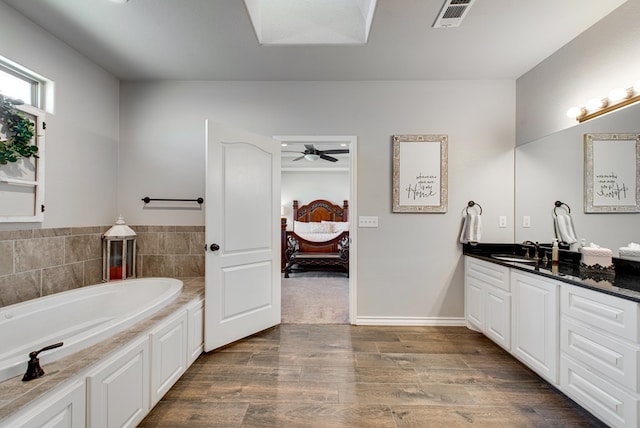 ensuite bathroom featuring visible vents, a garden tub, wood finished floors, connected bathroom, and vanity