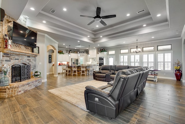 living room with dark wood finished floors, visible vents, a fireplace, and a tray ceiling