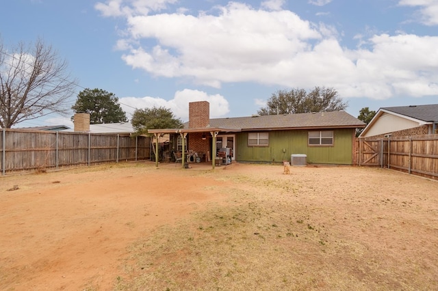 rear view of house featuring a fenced backyard, a chimney, cooling unit, and a patio