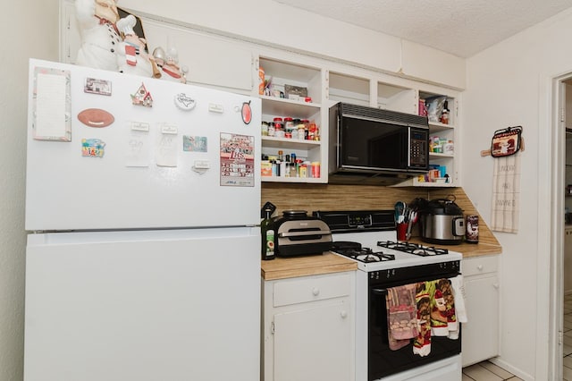 kitchen featuring black microwave, a textured ceiling, freestanding refrigerator, open shelves, and gas range oven