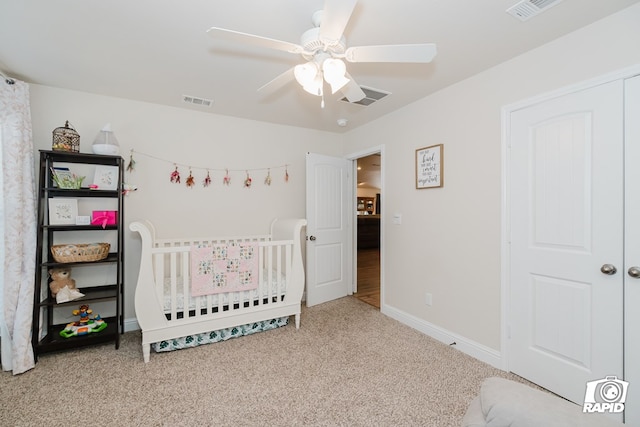 bedroom featuring ceiling fan, carpet, and a crib