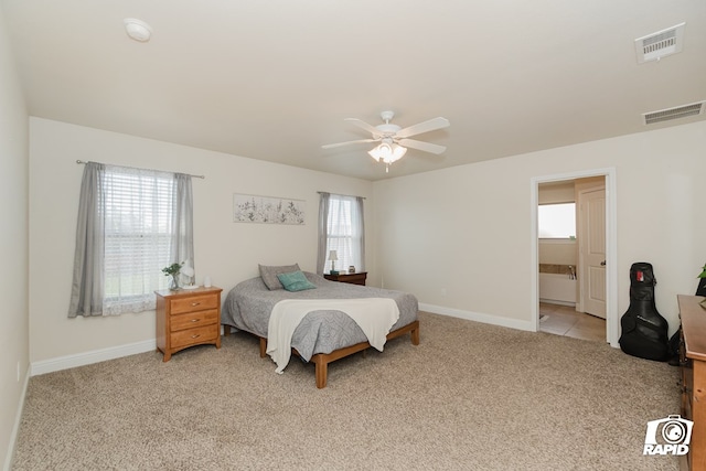 carpeted bedroom featuring multiple windows, ceiling fan, and ensuite bathroom