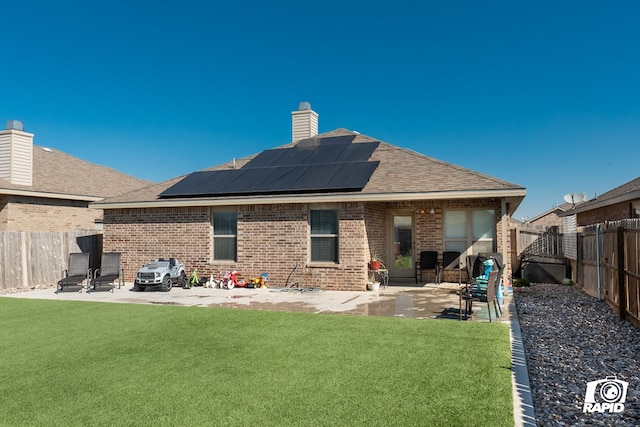 back of property with a lawn, a patio, and solar panels