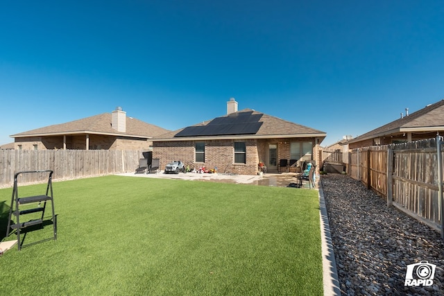 back of house with a patio area, a yard, and solar panels