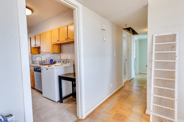 kitchen with light brown cabinetry, backsplash, stainless steel dishwasher, washer and clothes dryer, and sink