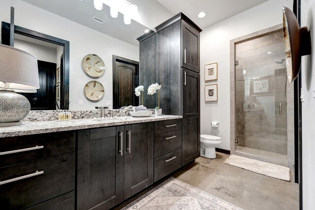 bathroom with toilet, a shower stall, vanity, and concrete flooring